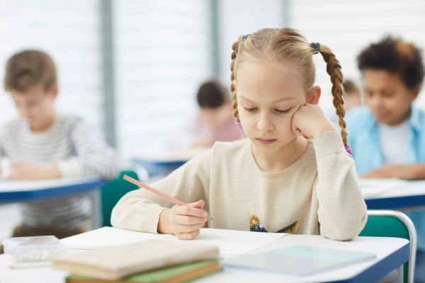 A young girl is engaged in writing in her notebook, showcasing concentration and creativity in a bright, inviting environment.